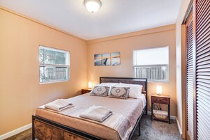 Camera da letto con un letto, due comodini, un'opera d'arte appesa al muro e finestre con persiane.