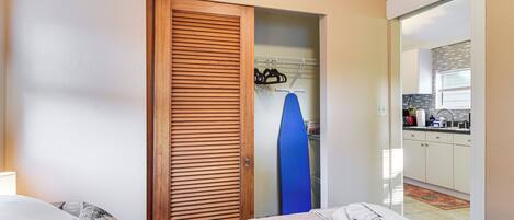 Ein Hotelzimmer mit Bett, einer Holztür, einem blauen Surfbrett und Blick auf die Küche.