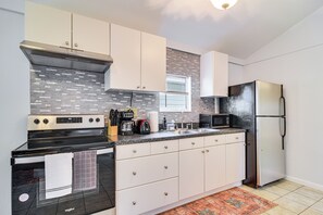 Une cuisine moderne avec des meubles blancs, une cuisinière en acier inoxydable, un four à micro-ondes et un réfrigérateur.