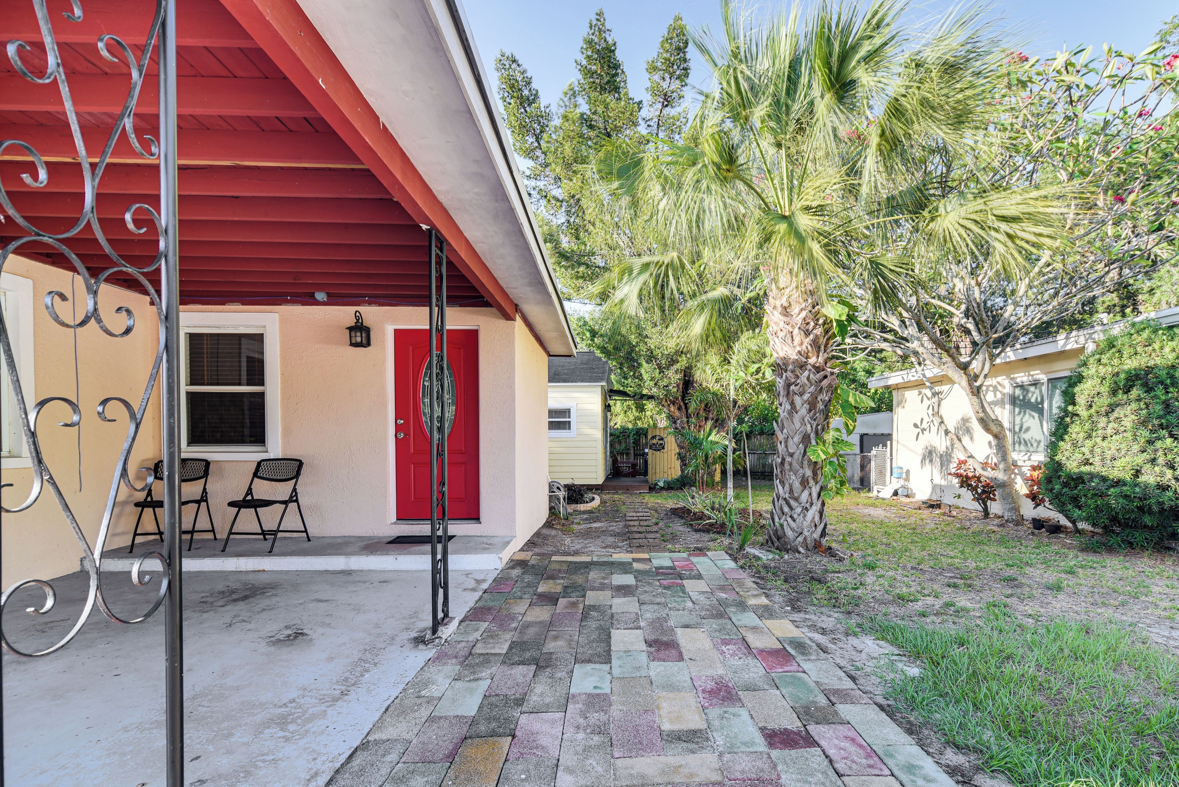 Ein Haus mit rotem Dach, einer Veranda mit zwei Stühlen und einer Palme.