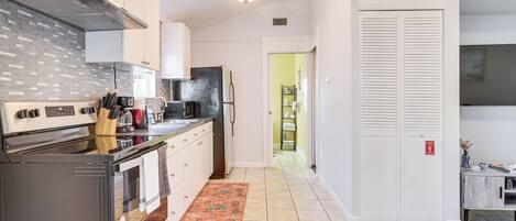 A modern kitchen with stainless steel appliances, white cabinetry, and a patterned rug.
