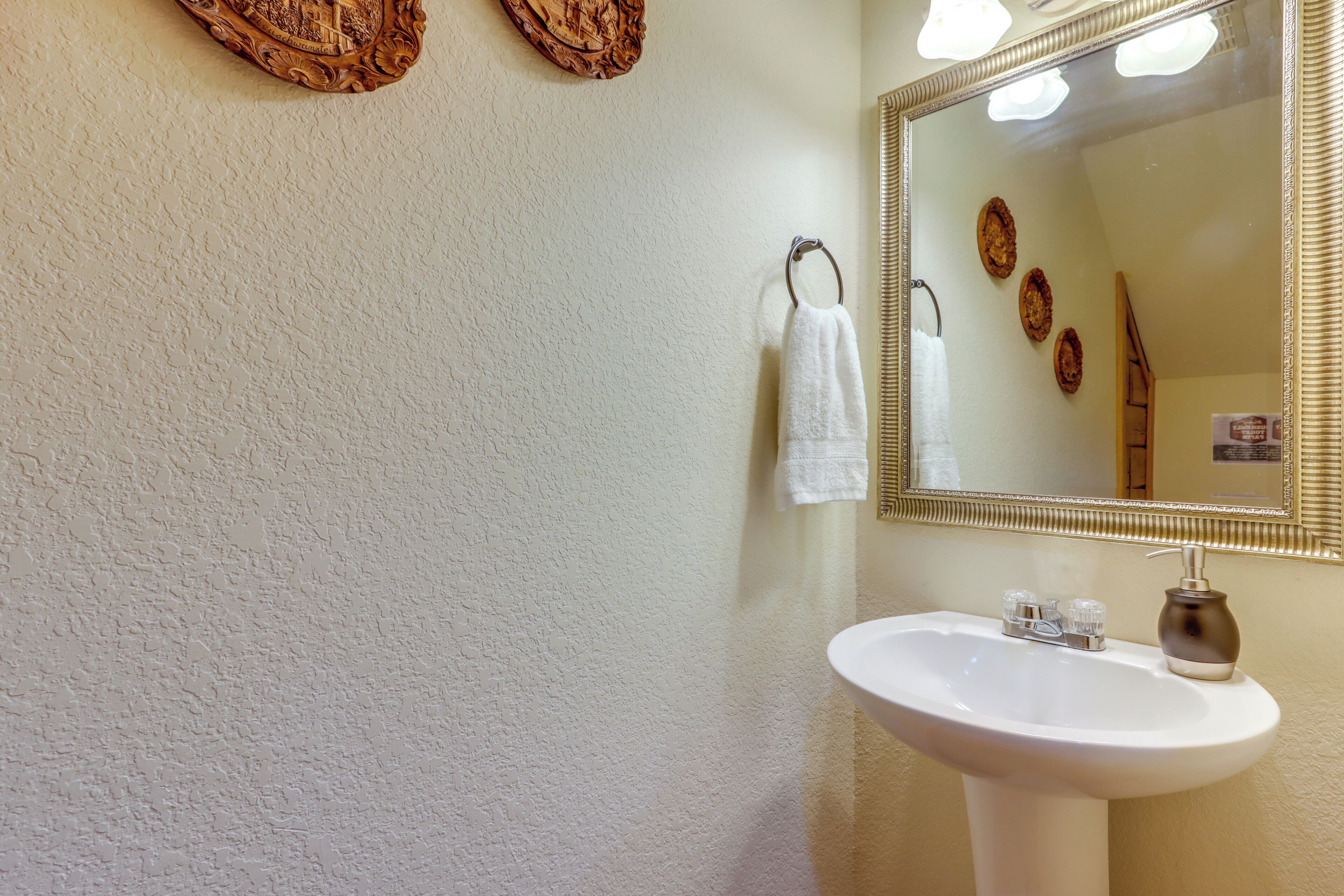 A bathroom with a white sink, a mirror, and decorative wall art.