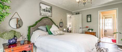 Un dormitorio con una cama grande, un tocador, un espejo y una araña.