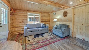 A log cabin interior with two sofas, a rug with animal motifs, and a wooden door.