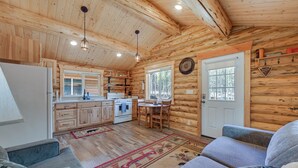 A cozy log cabin interior with a kitchen, dining area, and seating.