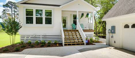 A single-story house with a front porch, a staircase leading to the entrance, and a small garden area.