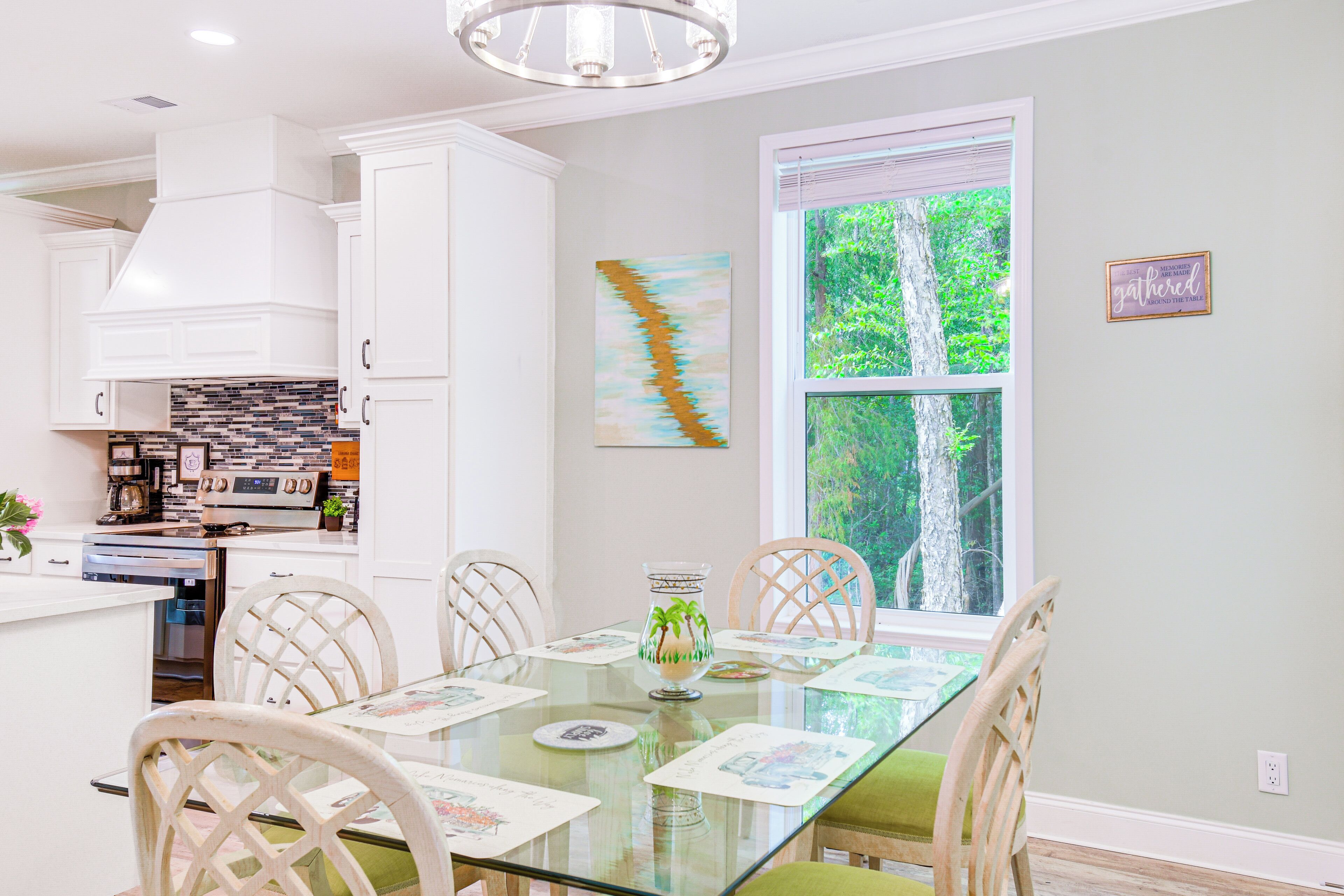A modern kitchen with white cabinets, a built-in oven, and a dining area with a glass table and chairs.