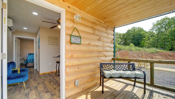 A wooden cabin interior with a wooden deck, a bench, and a blue chair.