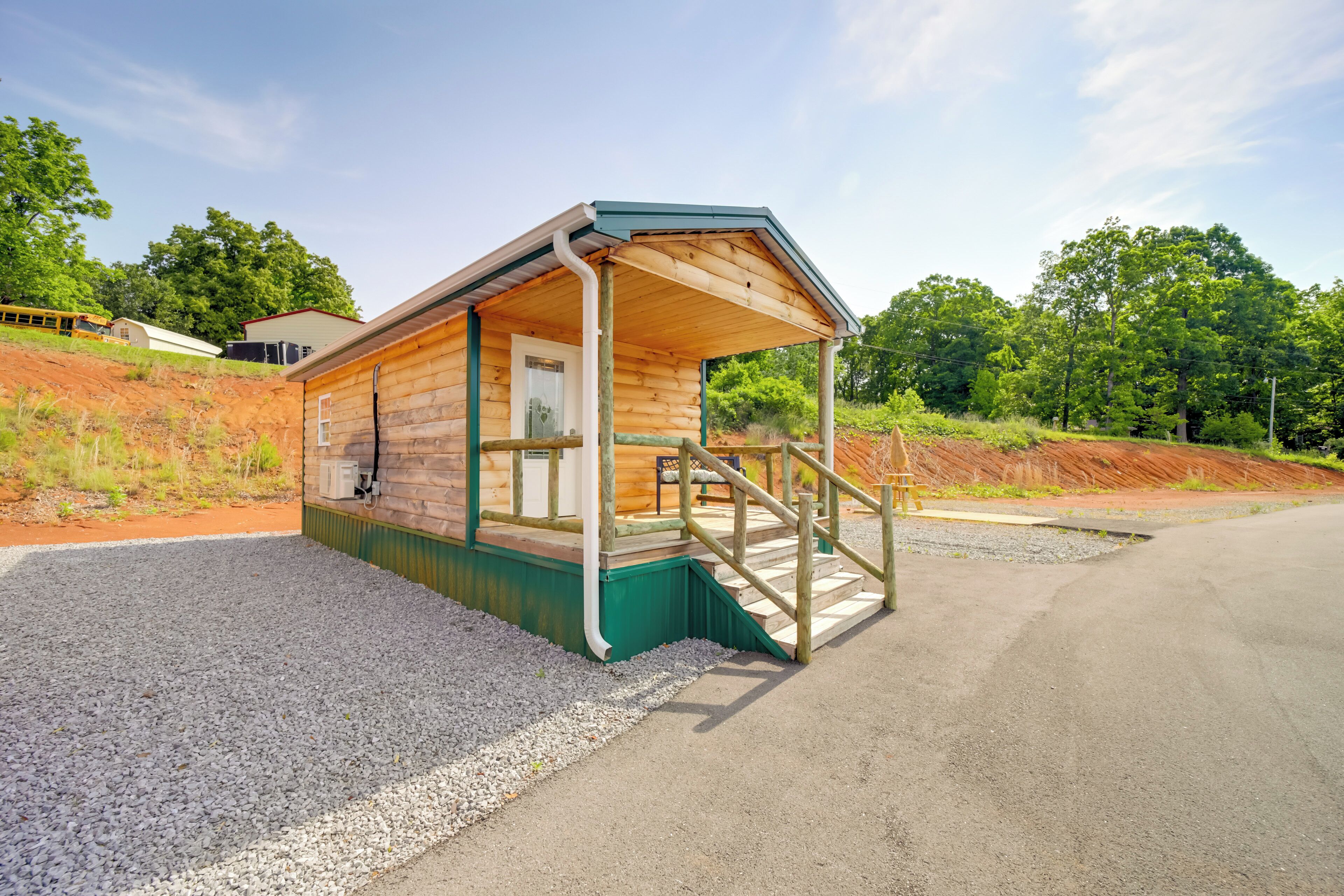 A wooden cabin with a porch, a small porch area, and a gravel driveway.
