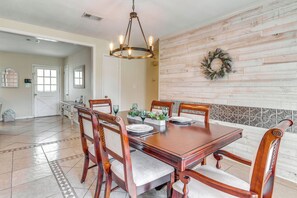 Un coin repas avec une table et des chaises en bois, un lustre et une guirlande décorative accrochée au mur.