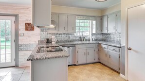 A kitchen with grey cabinets, a granite countertop, and a window with a view of greenery. - Pace Family Home: 1 Mi to Beach & Park! (Milton)