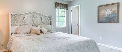 Un dormitorio con cama, ventilador de techo, ventana con cortinas y puerta.