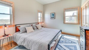 Un dormitorio con cama, mesita de noche, lámpara y vistas al exterior.