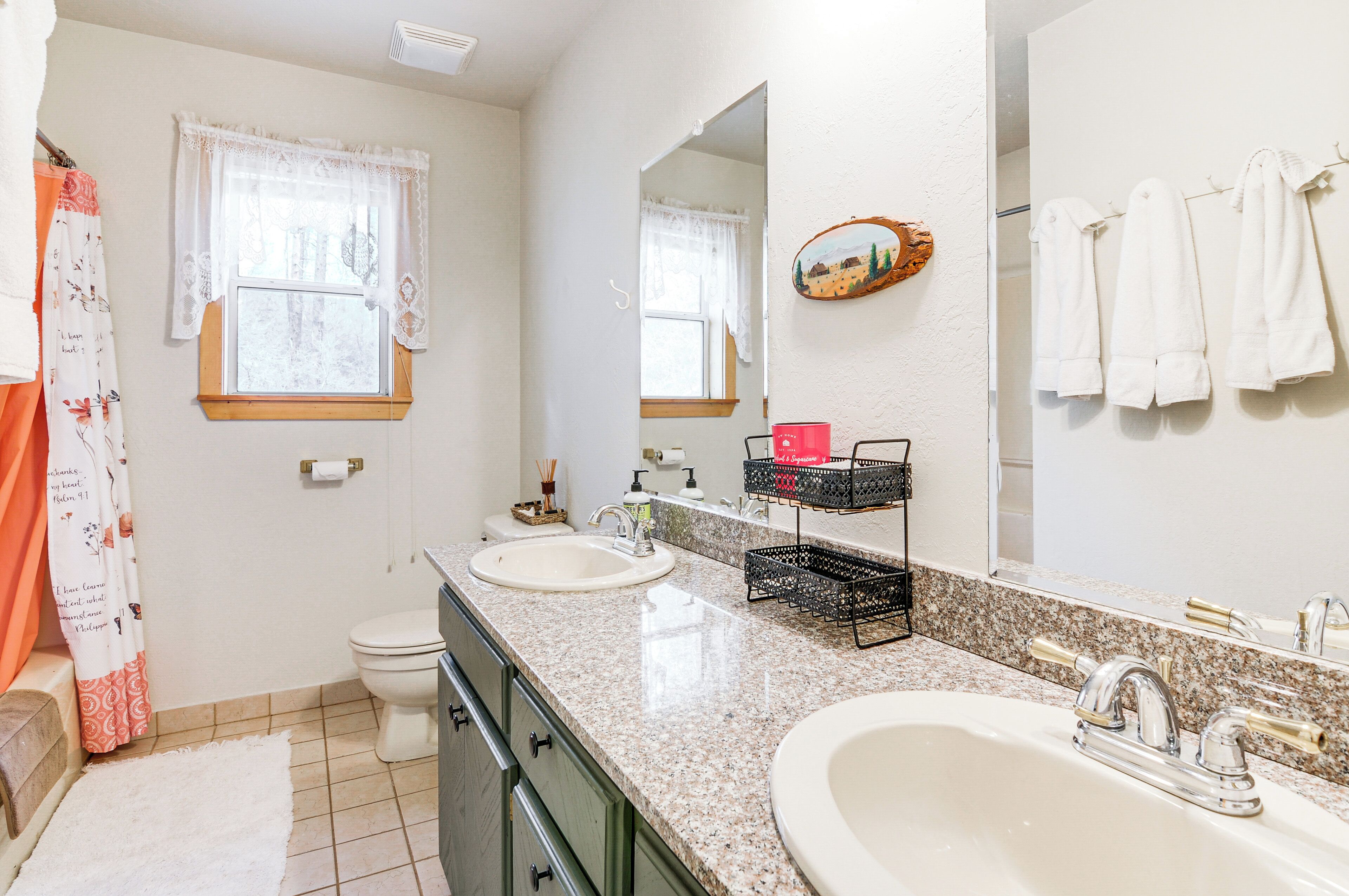 A bathroom with two sinks, a toilet, and a shower area.