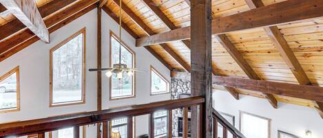 Un interior espacioso con techos altos, vigas de madera a la vista y grandes ventanales que ofrecen vistas al exterior.