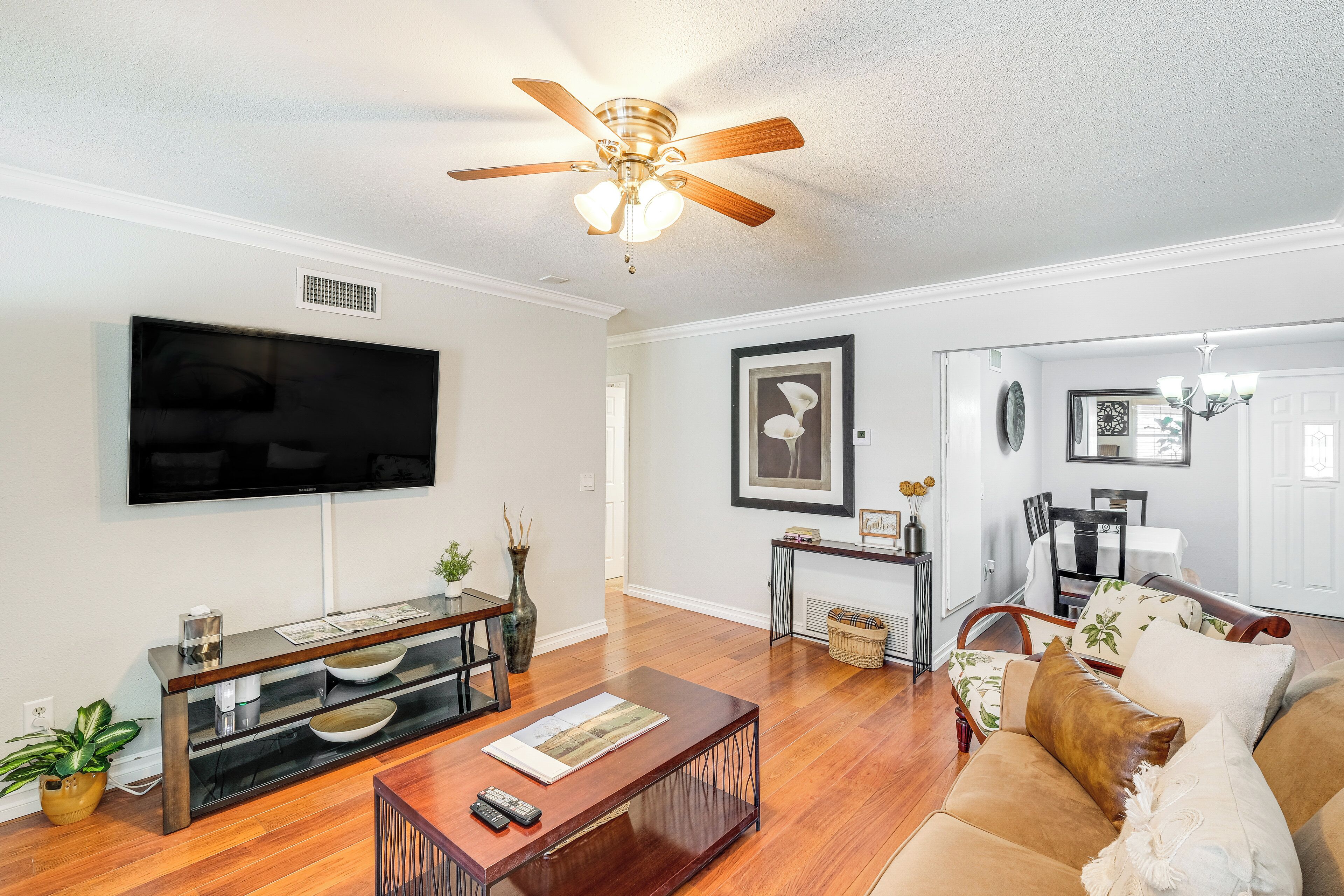 A living room with a flat-screen TV, wooden coffee table, and a ceiling fan.