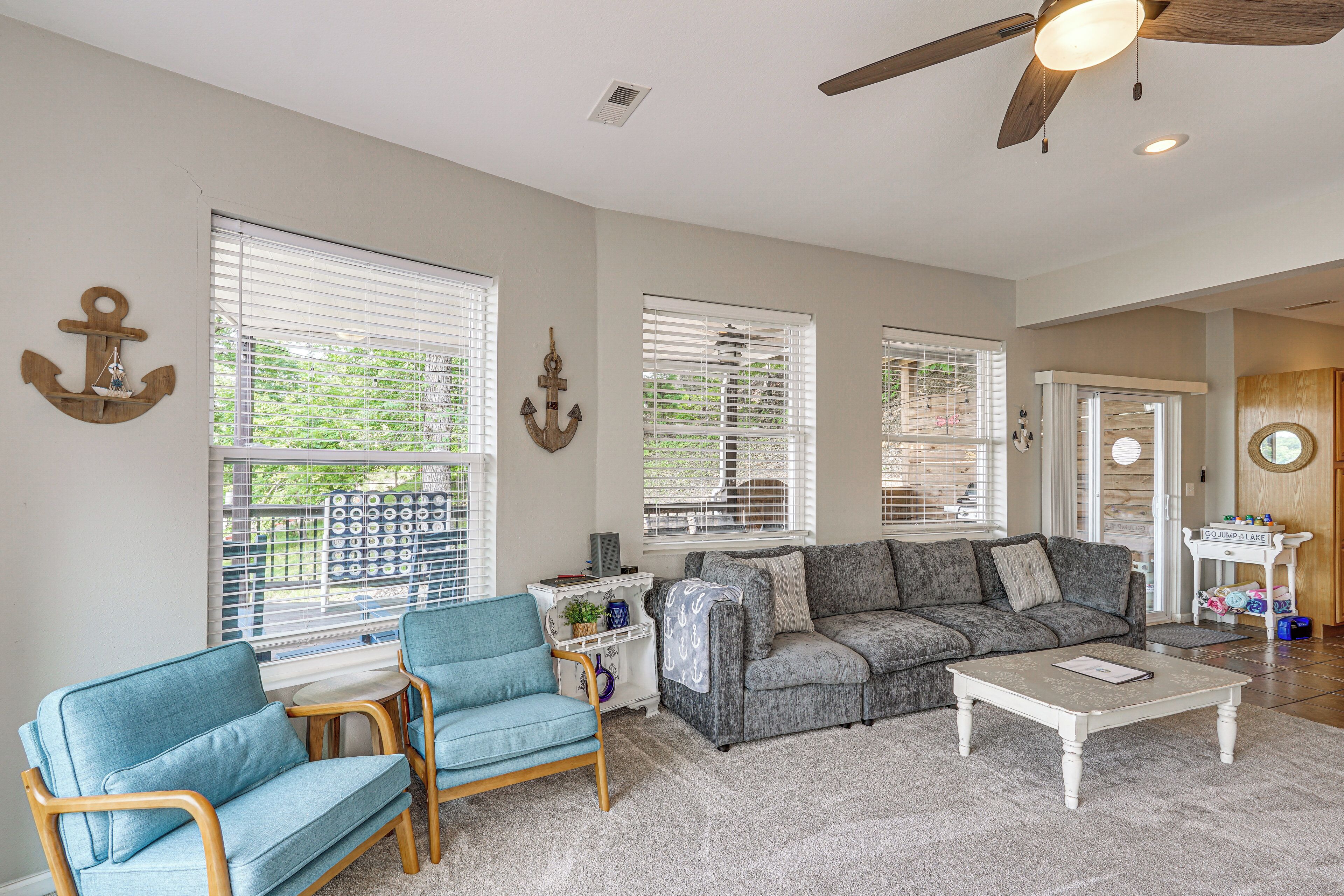 A living room with a gray sofa, blue armchairs, a white coffee table, and a ceiling fan.