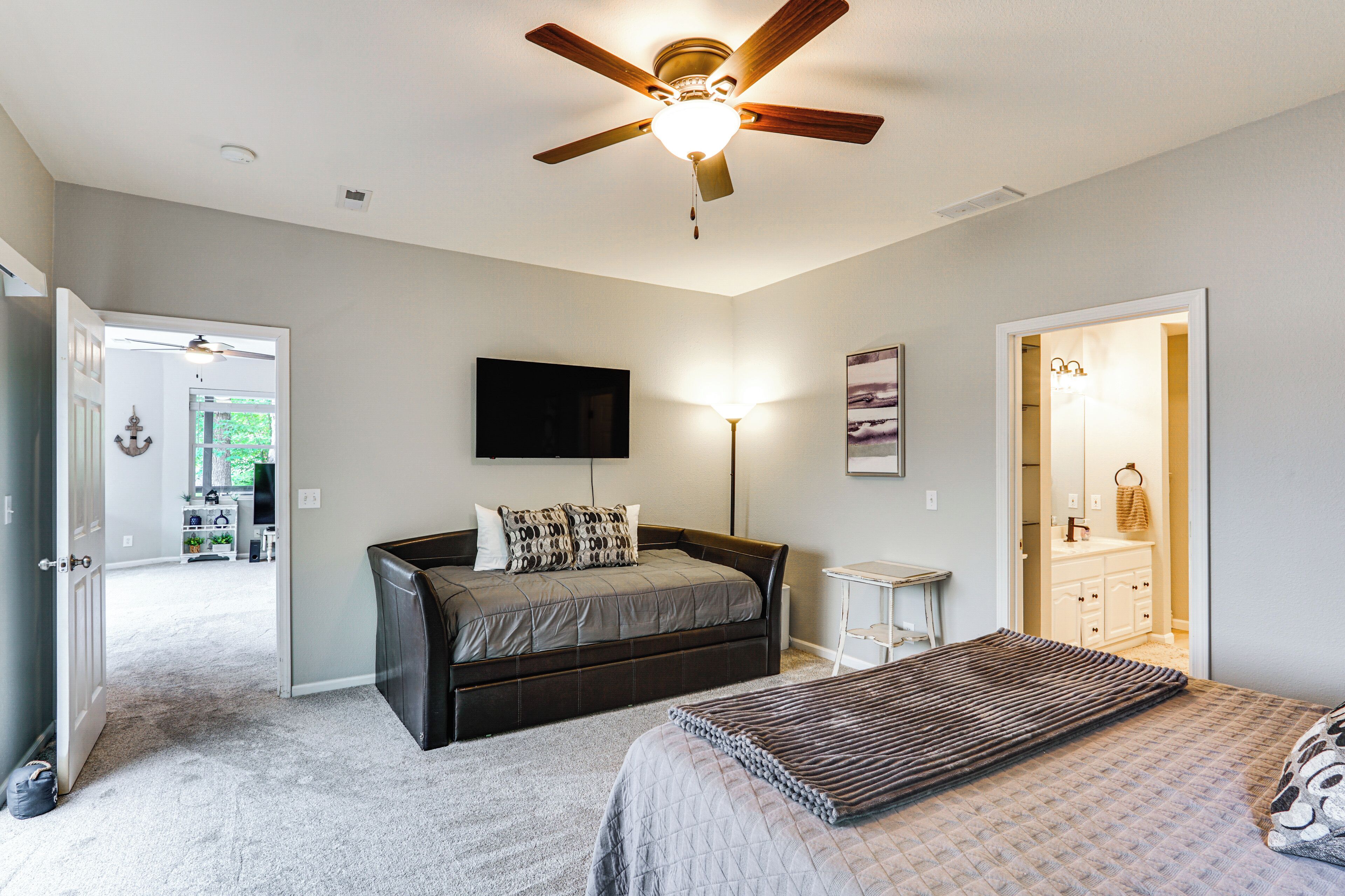 A bedroom with a bed, a bedside table, a ceiling fan, and a nightstand.
