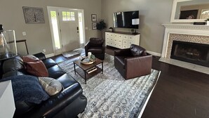 A spacious living room with a fireplace, a large TV, and a comfortable seating area.