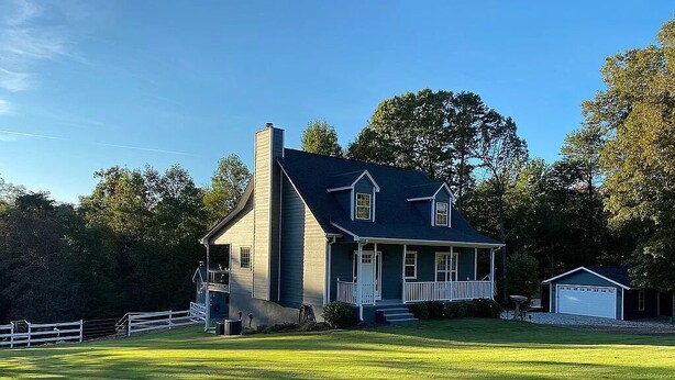 A two-story house with a front porch, a garage, and a well-maintained lawn.