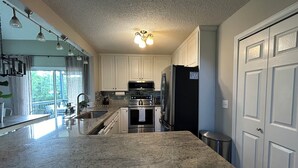 A kitchen with granite countertops, stainless steel appliances, and white cabinetry.