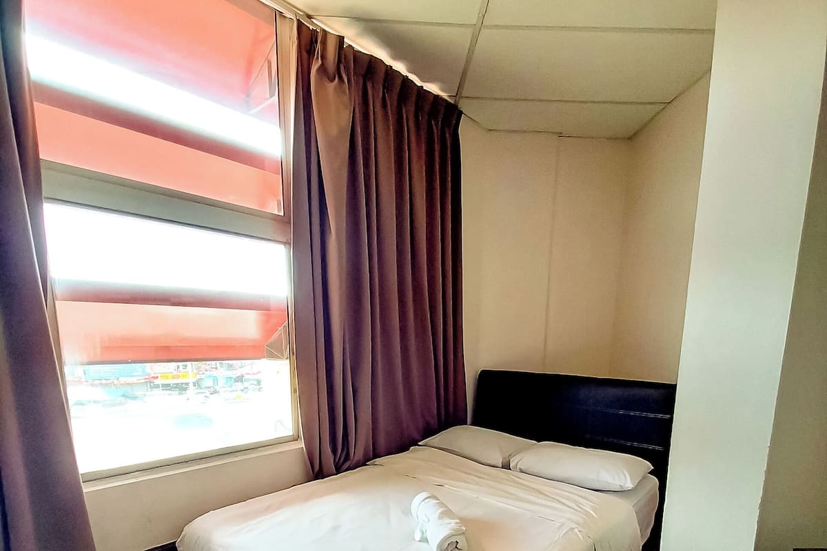 Una habitación de hotel con cama, ventana con cortinas y piso de baldosas.