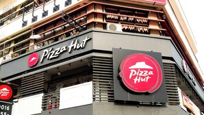 Un edificio de varios pisos con un Pizza Hut en la planta baja y un MB Budget Hotel en los pisos superiores.