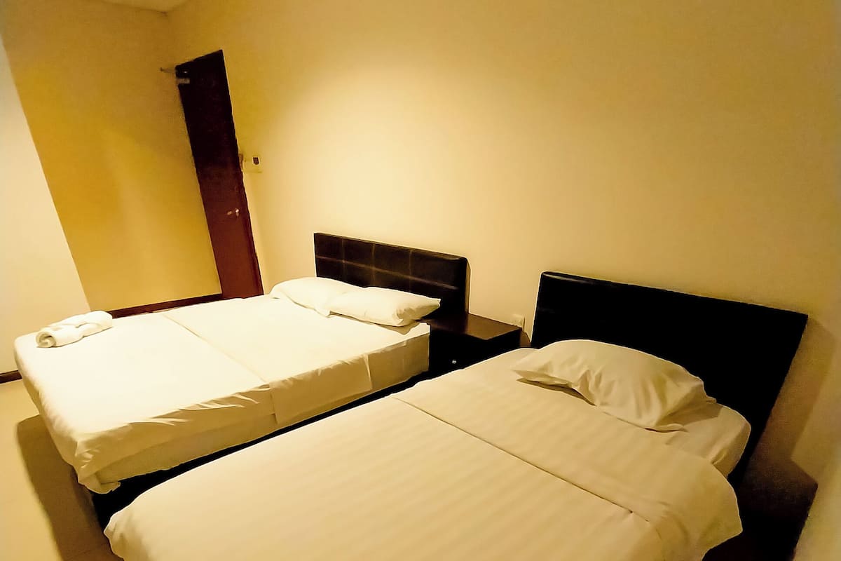 Una habitación de hotel con dos camas individuales, una mesita de noche y un teléfono instalado en la pared.