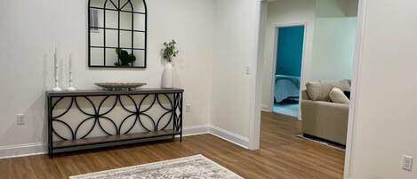 A modern living room with a console table, a decorative mirror, and a patterned rug.