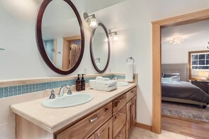 Un baño con dos lavamanos, armarios de madera y un espejo.