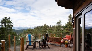 A wooden deck with outdoor furniture, including a table, chairs, and a sofa, overlooking a mountainous landscape. - Lookout Lodge In Wondervu 4 Bedroom Home by RedAwning (Golden)