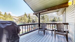 Puisesta laudasta rakennettu terassi, jossa on kaksi Adirondack-tyylistä puutarhatuolia ja grilli.