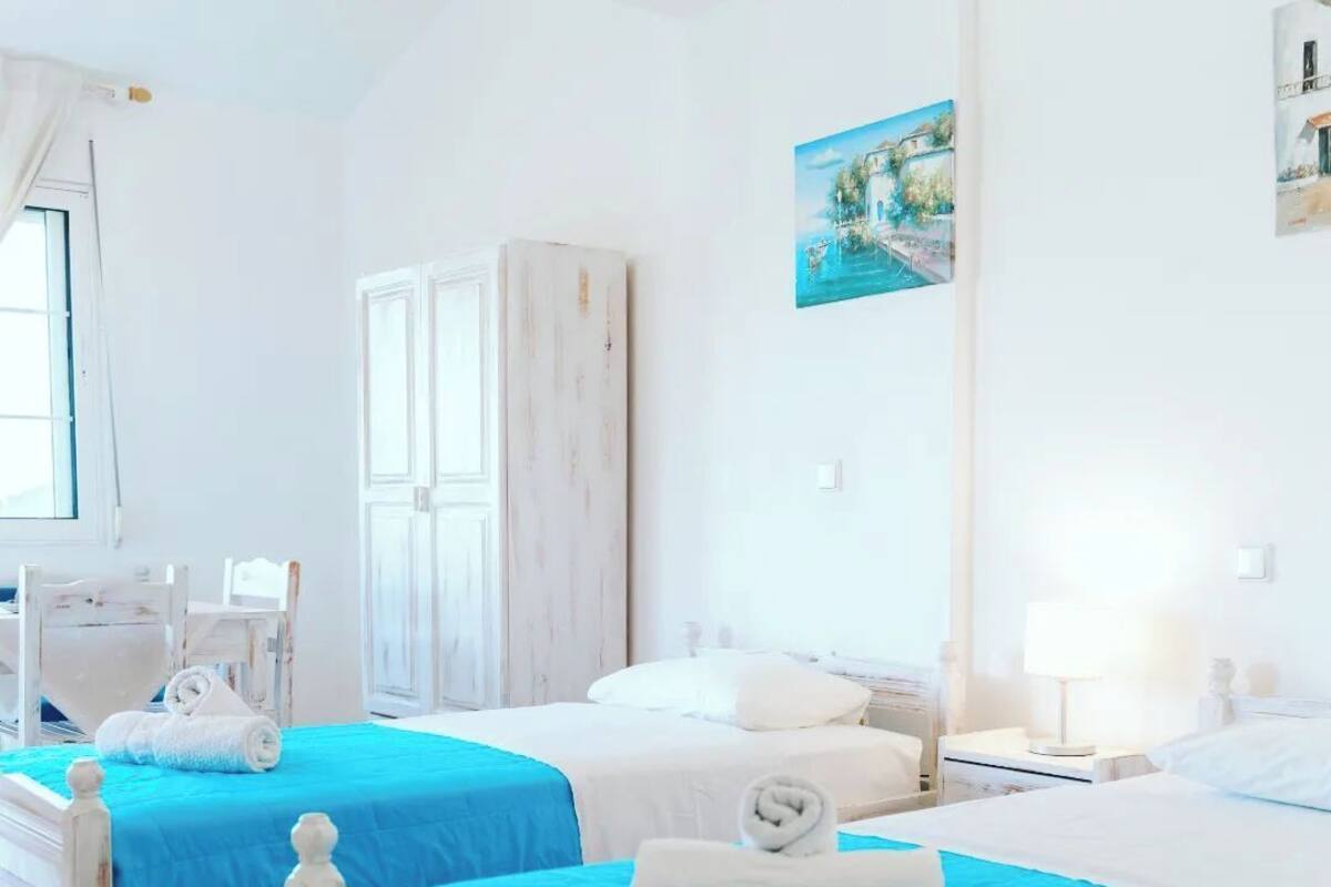 A hotel room with two beds, a wardrobe, a desk, and a painting on the wall.