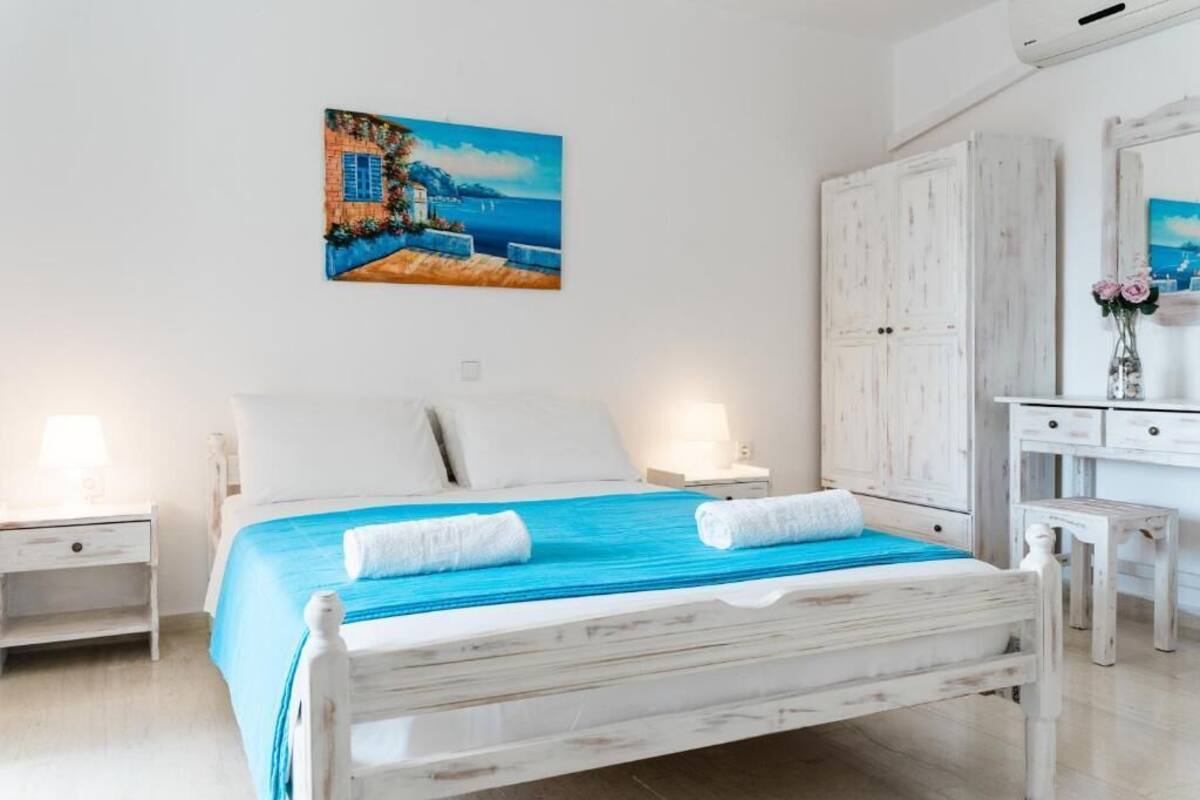 A bedroom with a bed, a nightstand, a dresser, and a painting on the wall.
