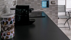 A modern kitchen with a black countertop, a coffee maker, and a wall-mounted oven. - The balcony overlooking the sea + parking space
 (Giardini Naxos)