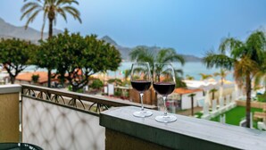 Two wine glasses on a balcony with a view of the sea and palm trees. - The balcony overlooking the sea + parking space
 (Giardini Naxos)
