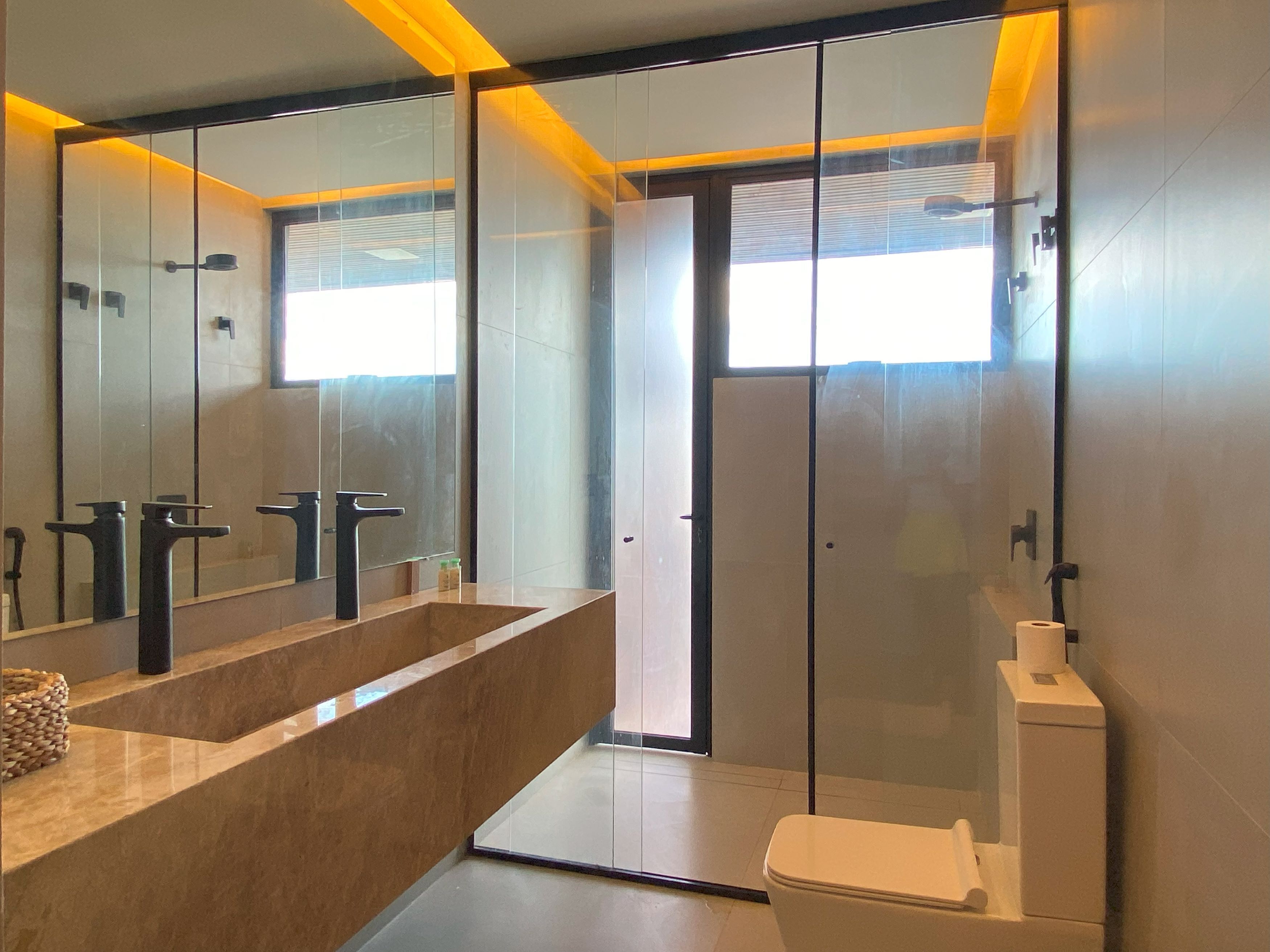 Un baño moderno con un espejo grande, dos lavamanos y un inodoro.