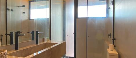 Un baño moderno con un espejo grande, dos lavamanos y un inodoro.