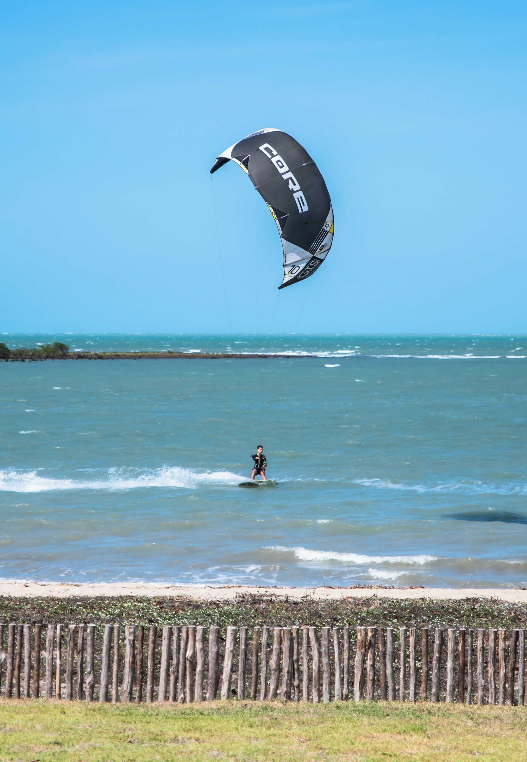 A person kiteboarding on a beach with a clear sky.
