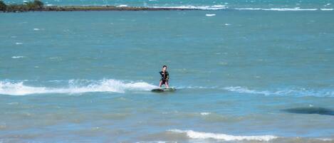 A person kiteboarding on a beach with a clear sky.