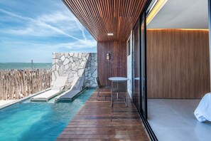 A wooden deck with a pool, stone wall, and a table with chairs. - Koloa Concept Hotel (Cajueiro da Praia)