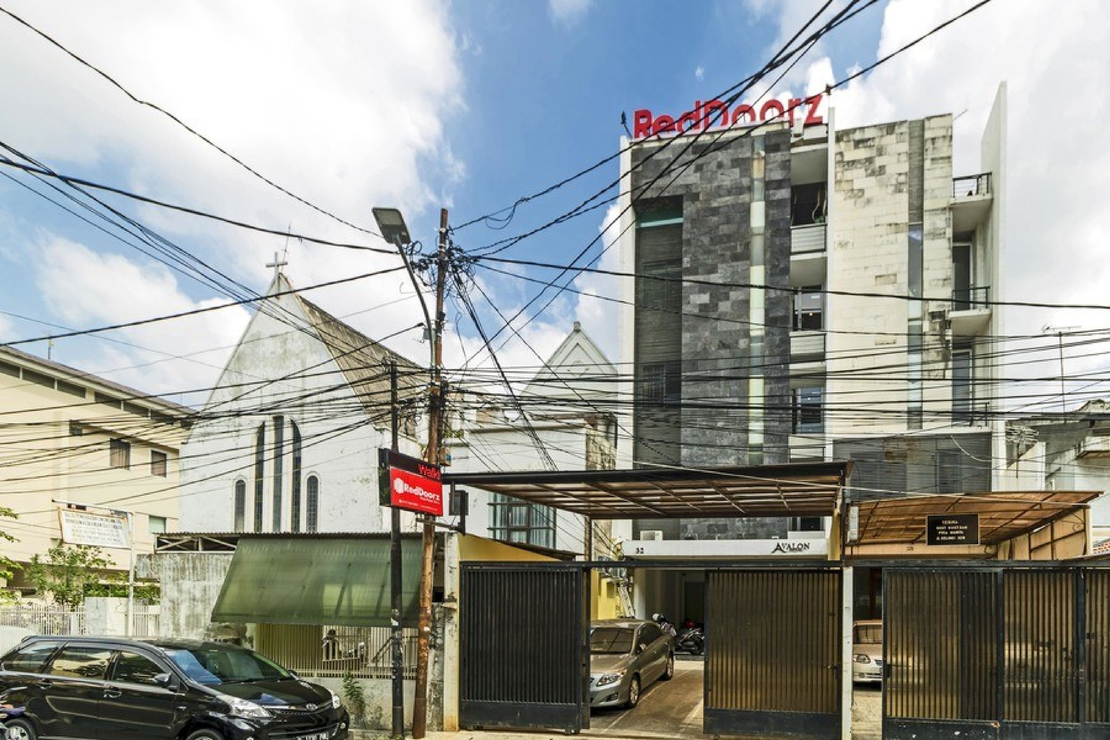 A building with a sign 'RedDoorz' and a gated entrance.