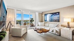 A modern hotel room with a large sliding glass door leading to a balcony with a city view.