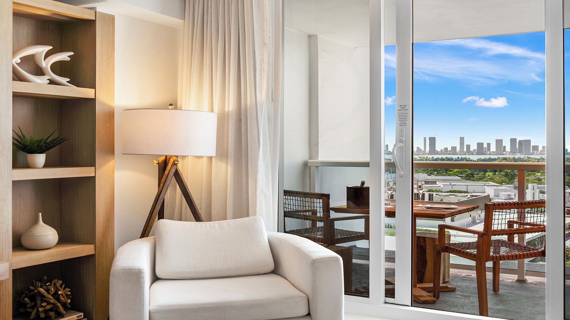 Un salon moderne avec un canapé, une lampe sur pied et une vue sur le paysage urbain, visible à travers de grandes fenêtres.