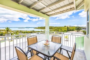 A balcony with a table and chairs overlooking a coastal view. - Chalk Sound | Lagoon Views | Walk to Sapodilla Bay (Providenciales)