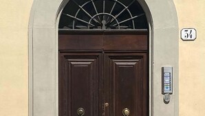 A double wooden door with a metal grill above it, set in a beige wall with a number '34' sign.