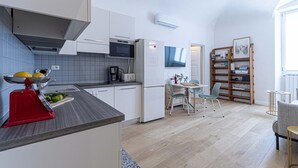 A modern kitchen with white cabinets, a red appliance, and a dining area with a table and chairs.