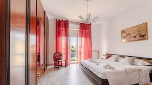 A bedroom with a bed, a chair, a painting, and a view through a door. - Italian Experience- Maison Loreto (Loreto)