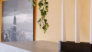 A framed cityscape photograph, a potted plant, and two white candles on a table. - Italian Experience- Maison Loreto (Loreto)