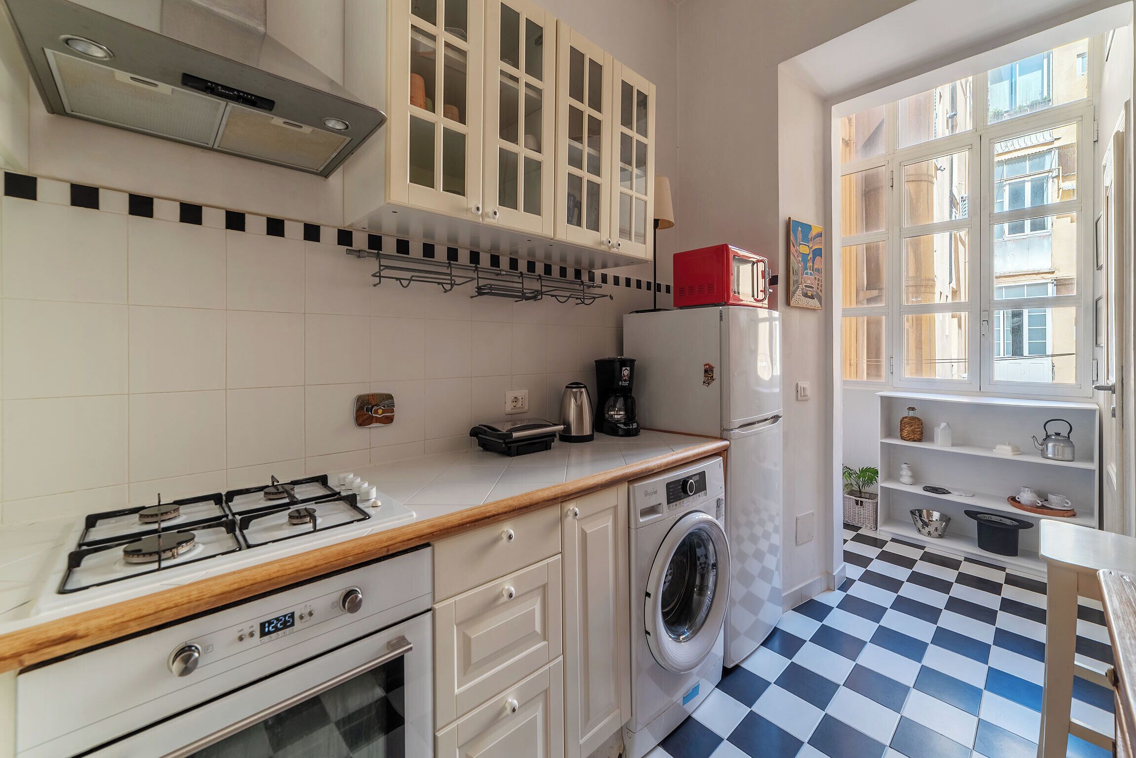 A compact kitchen with a gas stove, a washing machine, and a refrigerator.